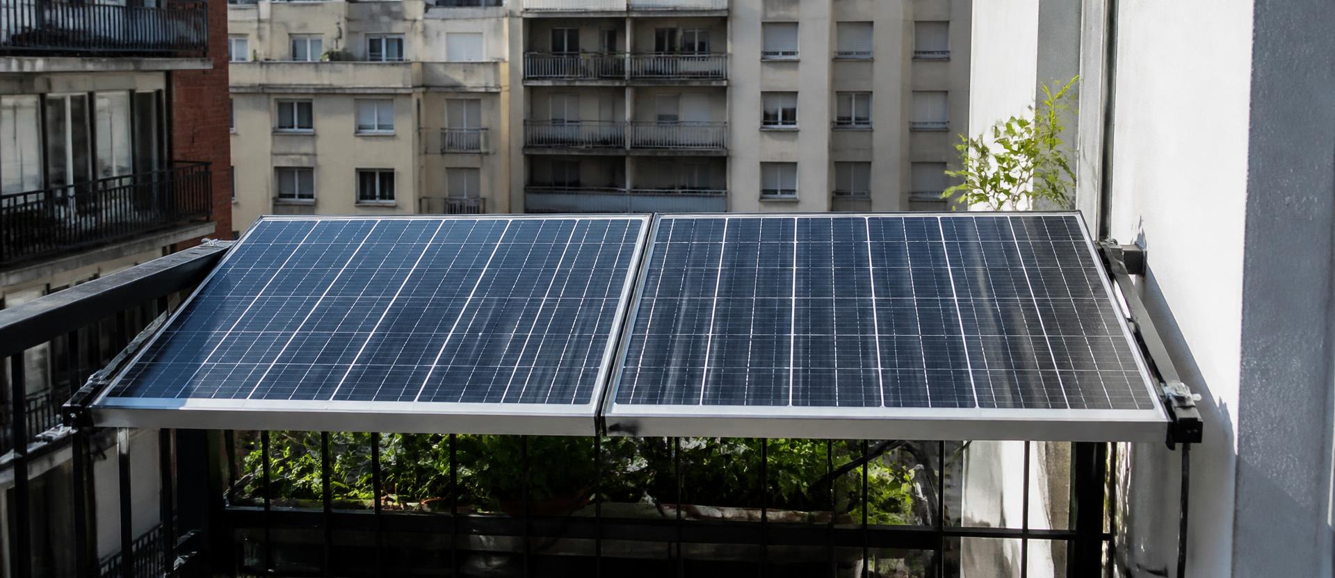 Două panouri solare de dimensiuni identice montate pe balustrada unui balcon îngust de apartament, în lumină puternică